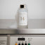 NOLES 14 Laundry Perfume auf Waschmaschine stehend mit Schaum um die Flasche