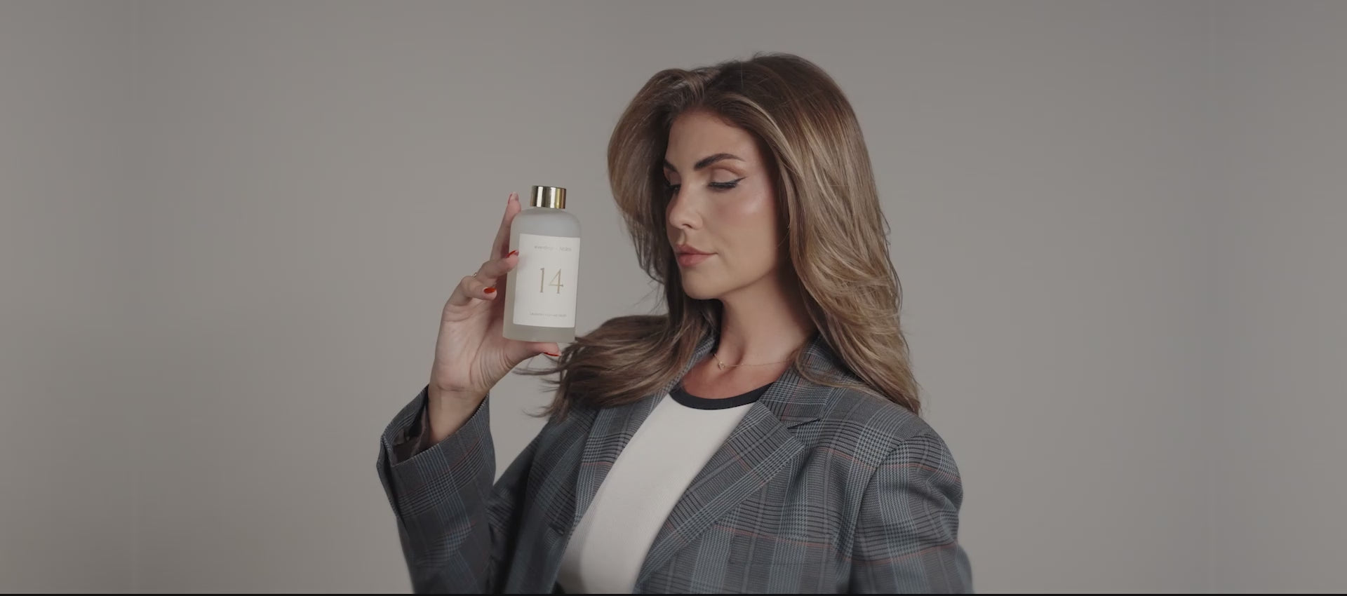 Farina vor grauem Hintergrund mit NOLES 14 Laundry Perfume in der Hand 