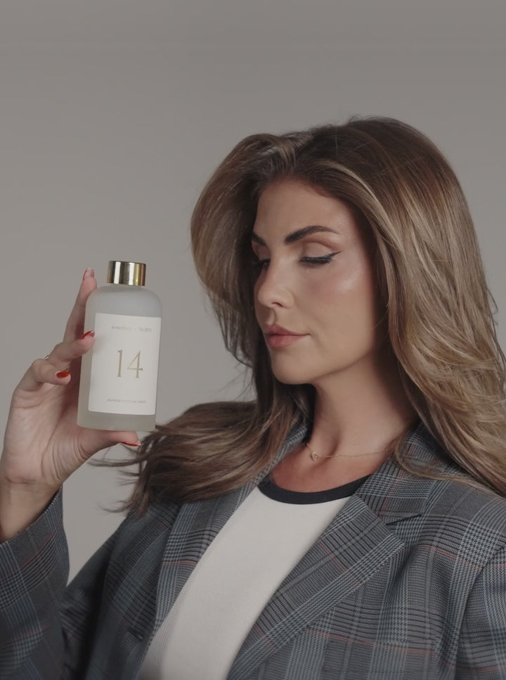 Farina vor grauem Hintergrund mit NOLES 14 Laundry Perfume in der Hand 